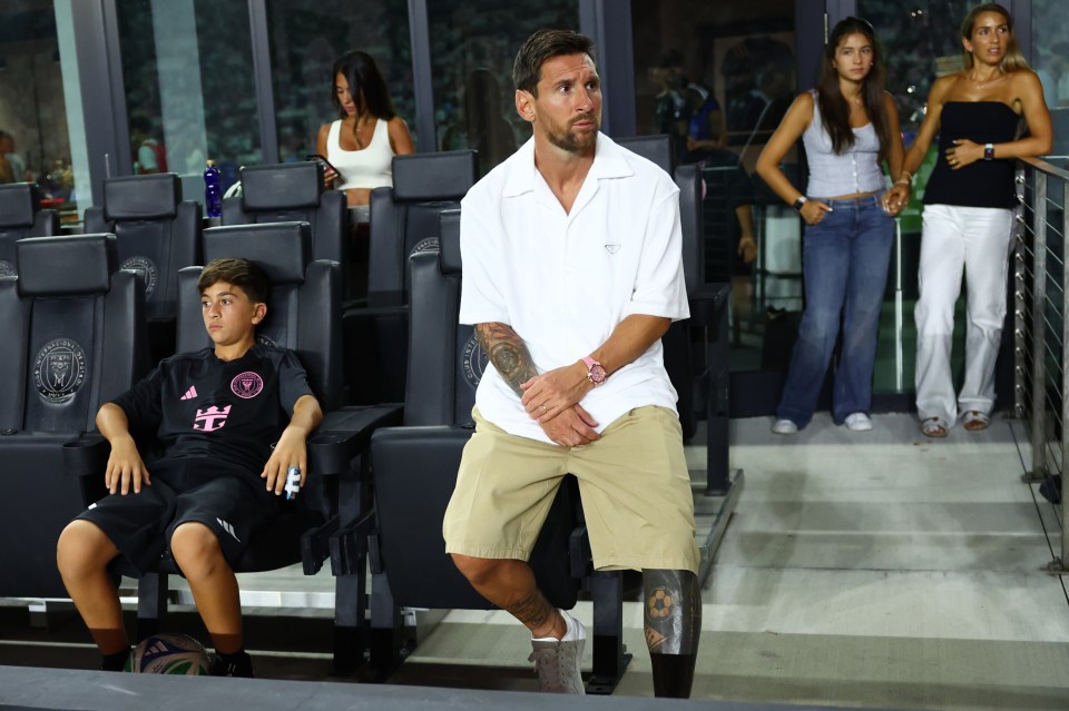 Lionel Messi and his son sitting in stadium seats.