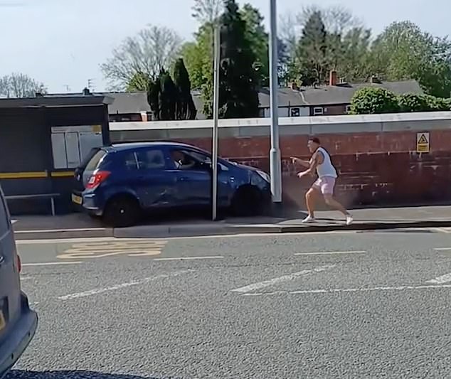 Shocking footage showed a driver trying to mow down a passer-by in a small blue car as he ran along the road in fear and was only saved by a lamp post