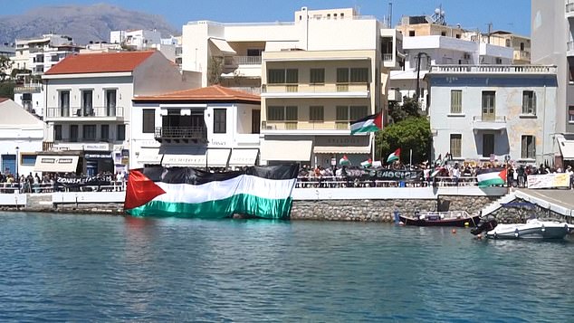 Protestors unveil a huge Palestine flag to greet the Israeli cruise ship as it arrives into port
