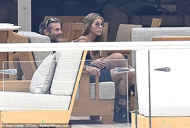 A relaxed Aniston was seen resting her hand on Curtis' thigh as they chatted with friends in an intimate moment - with an insider dishing on the twice divorced star's newfound happiness