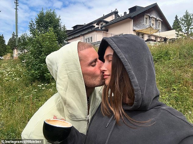 Justin and Hailey Bieber looked to be happy as ever in a new image shared to Instagram on Wednesday. The pop prince was seen kissing his supermodel wife while on a vacation in what appears to be Switzerland