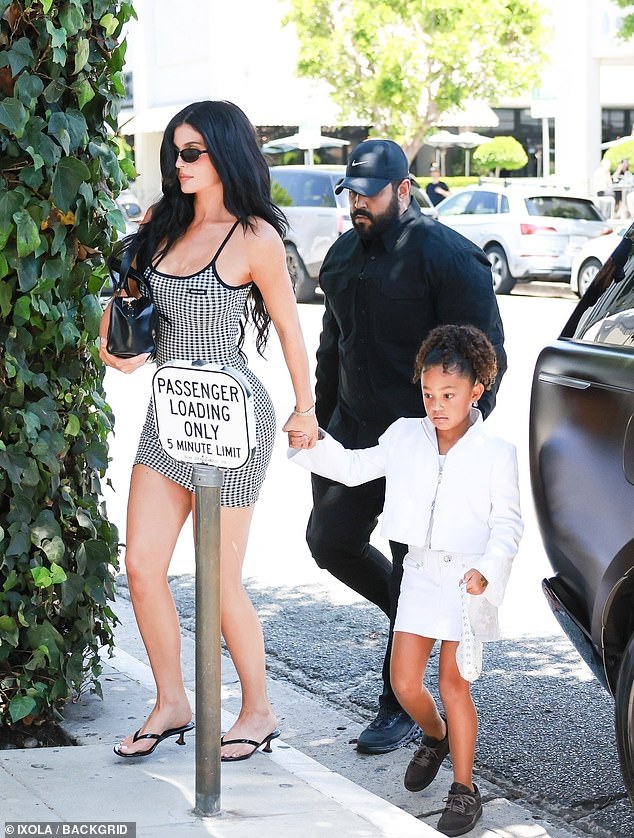 The 27-year-old cosmetics mogul slipped her curves into a patterned black and white body-con mini dress as she held hands with seven-year-old daughter Stormi