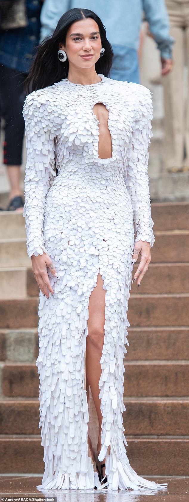 Dua Lipa wore a outfit from Schiaparelli's Spring/Summer 2024 show ¿ a floor length white gown with a cutaway keyhole detail, decorated entirely with fluttering, feather-like paillettes