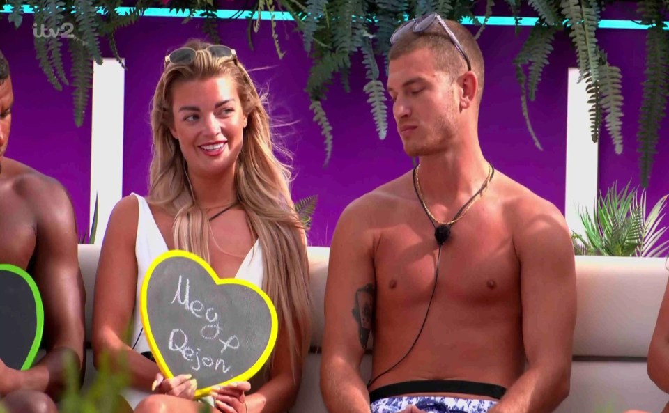 Love Island contestants Meg and Dejon holding a heart-shaped sign.