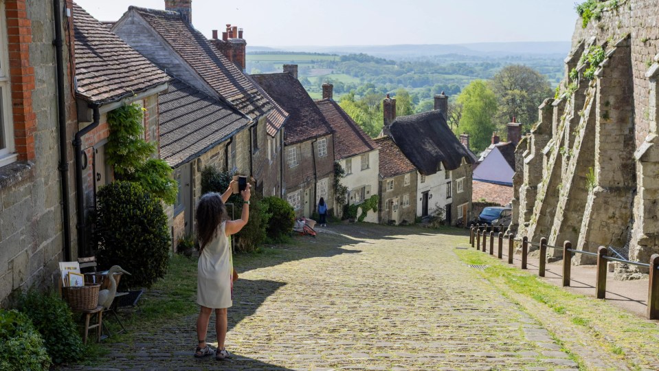 A tourist taking a picture of Gold Hill in Shaftesbury, England.