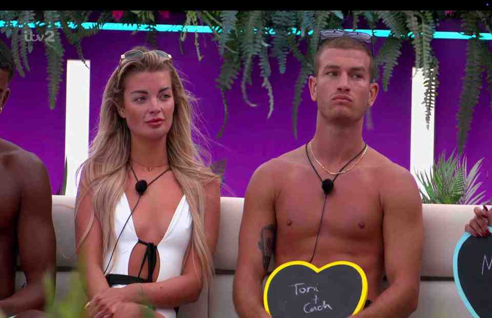 Love Island contestants Tom and Cach holding heart-shaped slates.