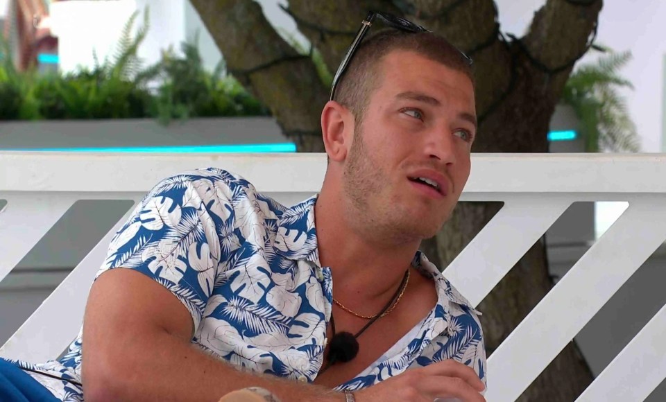 Man in a floral shirt sits and talks.