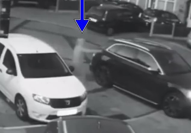 A woman dressed in a burka can be seen approaching a black SUV and firing a gun but it jams