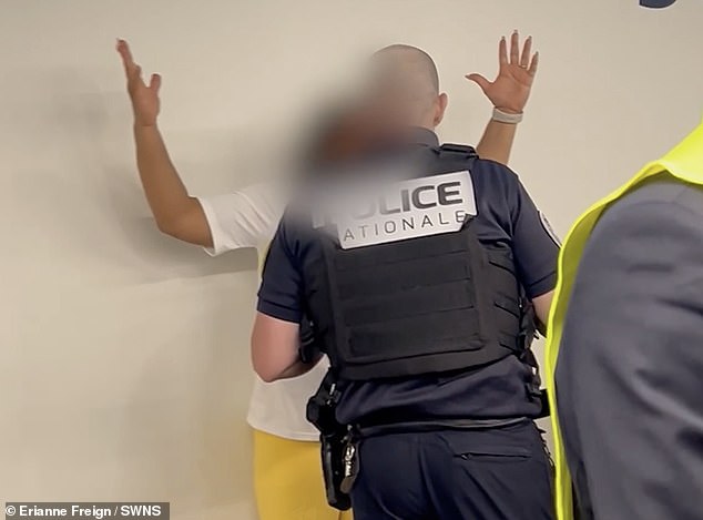 The woman, pictured in white and yellow, is seen being detained by police at the airport
