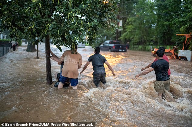 Men hold on to a tree after being caught in raging flood waters in Plainfield, New Jersey