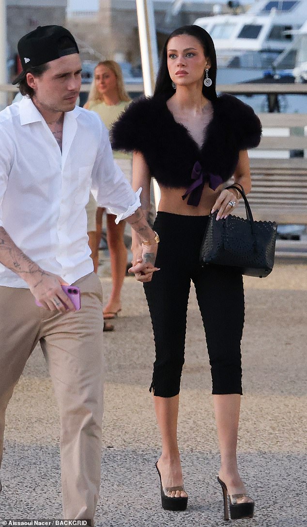 The billionaire heiress, 30, held onto the 26-year-old aspiring chef's hand and while he flashed a smile she looked stony faced