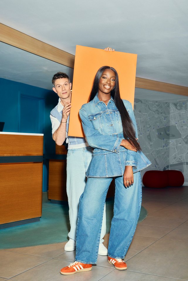 Two people posing in a hotel lobby, holding up a large orange sign.