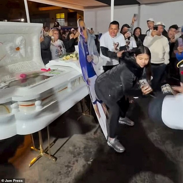 A young woman in Peru was caught on camera twerking against a life-sized cut-out of her late husband leaning against his open coffin.