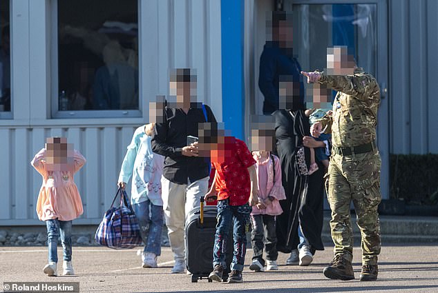 A British soldier welcomes an Afghan family to Britain and points them towards their coach as part of a secret scheme exposed by the Daily Mail to bring migrants into Britain