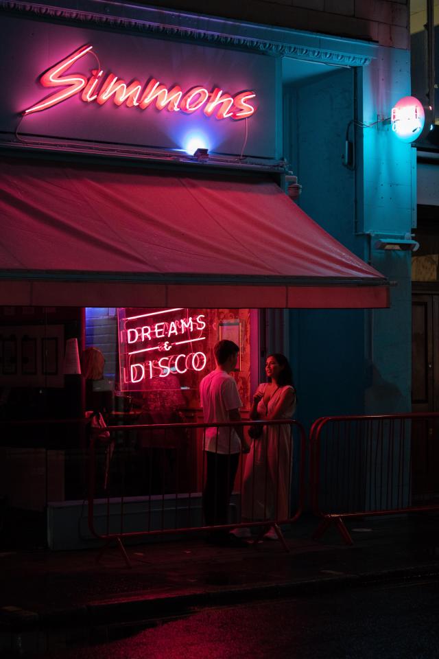 Couple standing outside Simmons club in London at night.