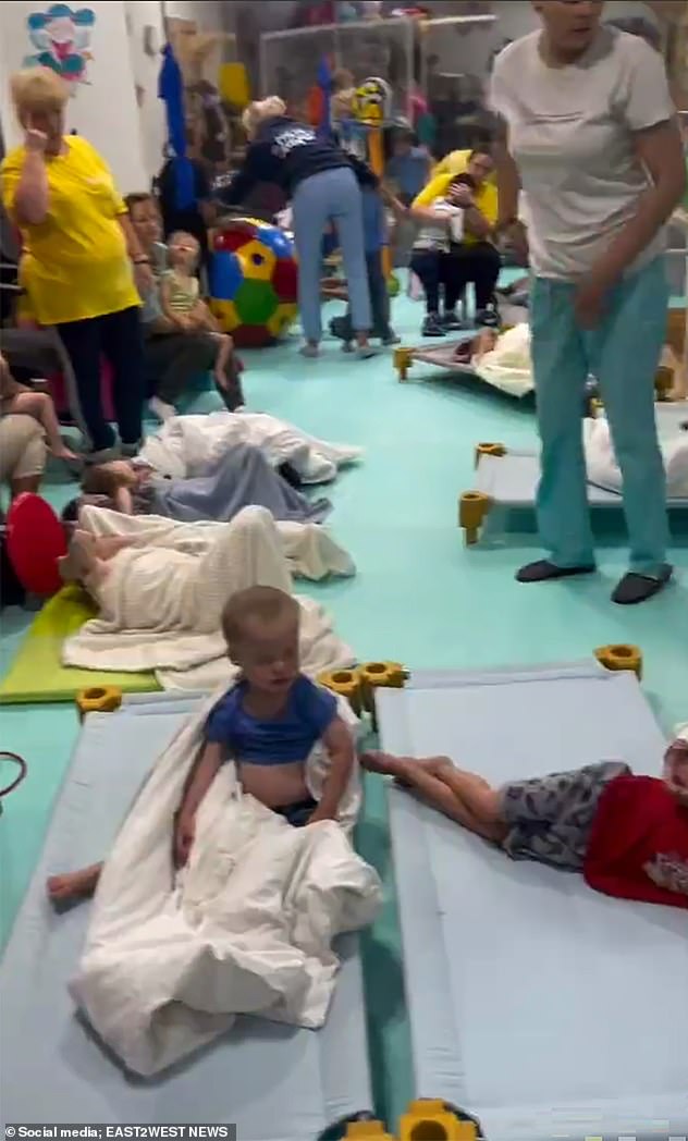 The harrowing footage was from the night of 9-10 July, but has only now appeared. 'This is how the children were evacuated to a shelter in the Butterfly House in Chernivtsi,' said the caption. Pictured: Children lying on mats in the bomb shelter. In the background a nurse appears to be comforting one of the orphans