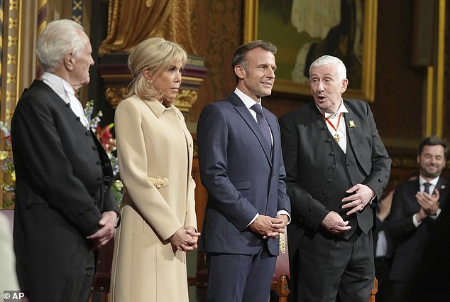 French President Emmanuel Macron and his wife, Brigitte, stand beside the Speaker of the House of Commons Lindsay Hoyle, right