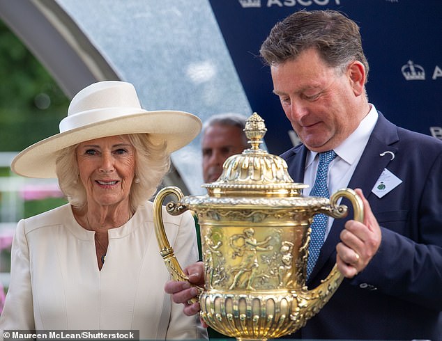 Queen Camilla presents the winner's trophy as she enjoys a day out at Ascot