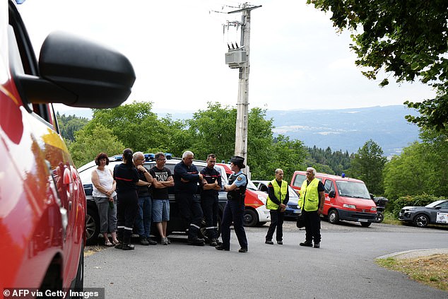A police officer and rally officials gather near the crash site after a car veered off the road and struck spectators during the Rallye de la Fourme d'Ambert in France