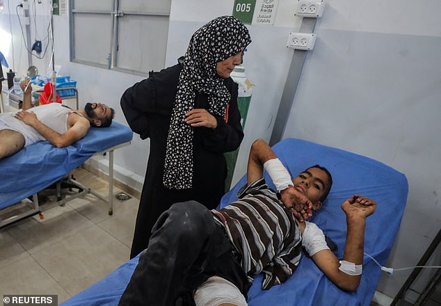 Pictured: A Palestinian boy, wounded in an Israeli strike that killed people, who gathered to collect water from a distribution point