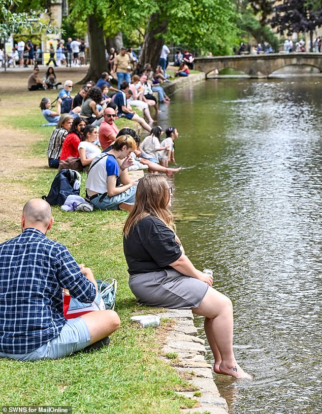 Tourists line the grass verges along the River Windrush in Bourton-on-the-Water on July 17 - one of the busiest months for visitors in the village