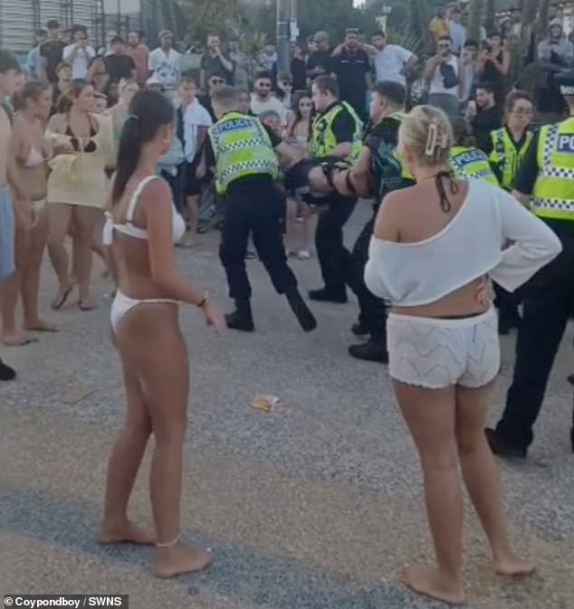 Police carry away a detained individual after a mass brawl on Bournemouth beach last week
