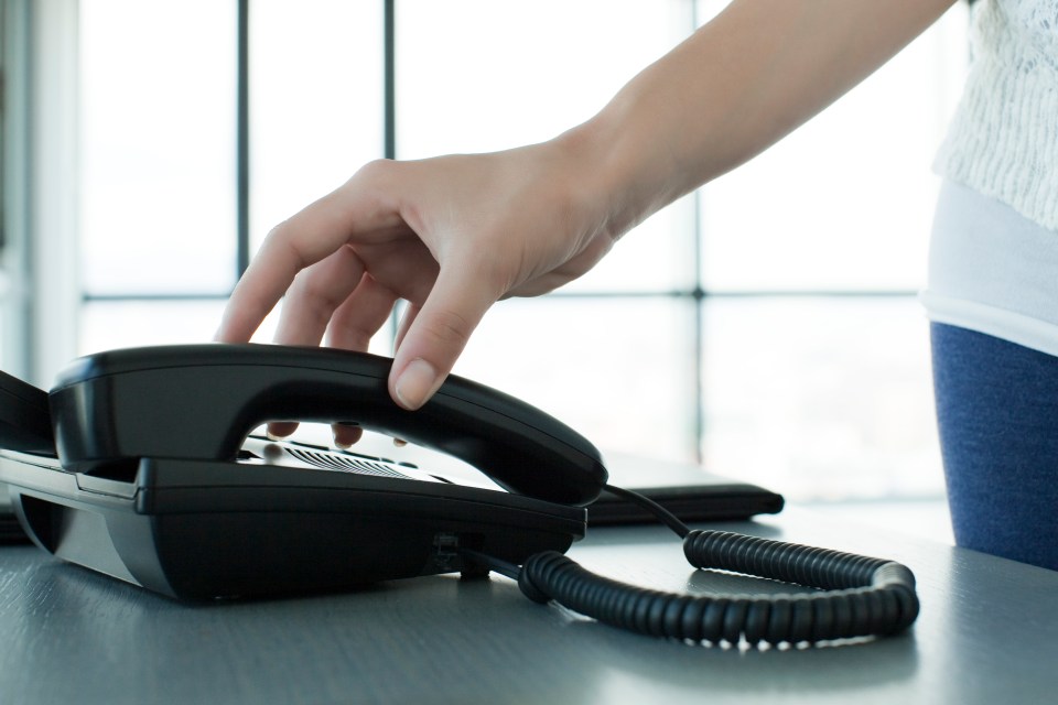 Woman's hand picking up a telephone receiver.