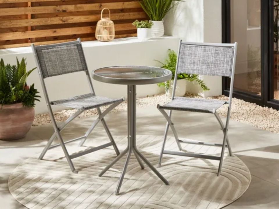 Small patio set with glass-top table and two folding chairs.