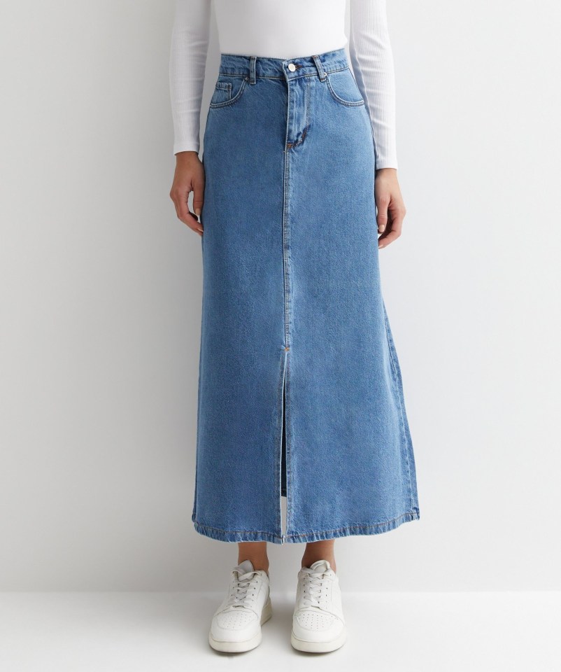 Person wearing a long denim skirt and white sneakers.