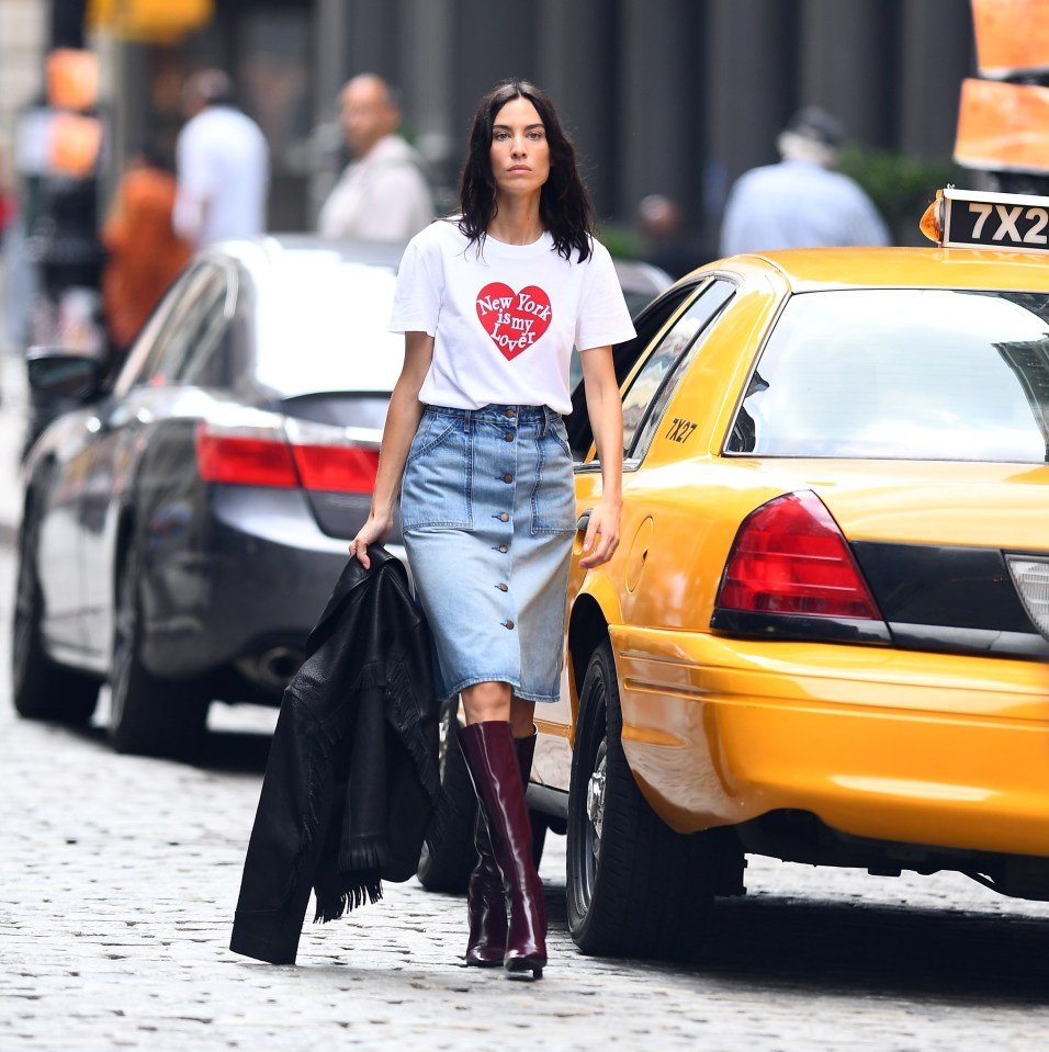 Alexa Chung in New York City during a photoshoot for Madewell, wearing a denim skirt, white t-shirt, and burgundy boots.