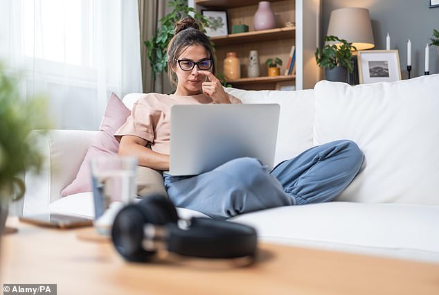 Pictured: woman working from home, sat on the sofa with a laptop on her lap. More and more Brits are now working from home