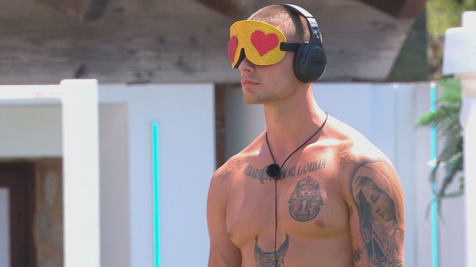 Man wearing heart-shaped eye mask and headphones.