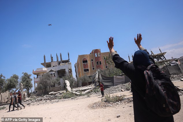 A Palestinian woman in northern Gaza's Jabalia gestures at a plane conducting an airdrop of aid in the Israel-besieged Palestinian territory on August 1, 2025