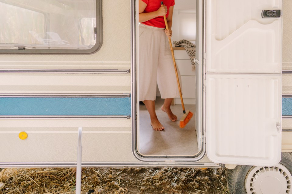 Woman sweeping the floor of her camper van.