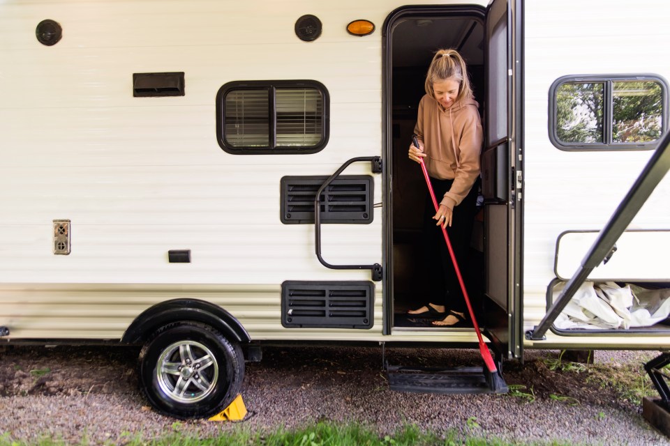 Woman sweeping in front of her RV.