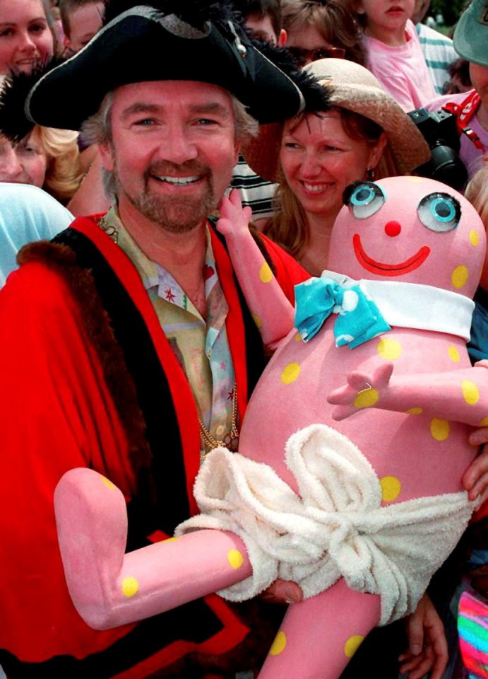 A man in a pirate costume holding a large pink character.