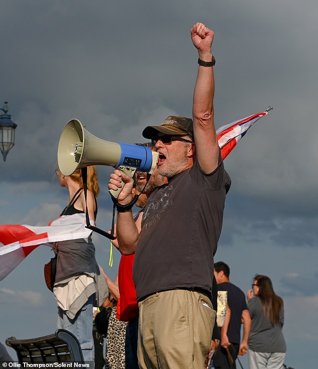 An anti-migrant protester speaks to the crowd through a megaphone