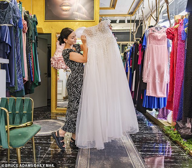 Wedding store shop assistant Dorian Laci shows off one of the many wedding dresses available to hire out