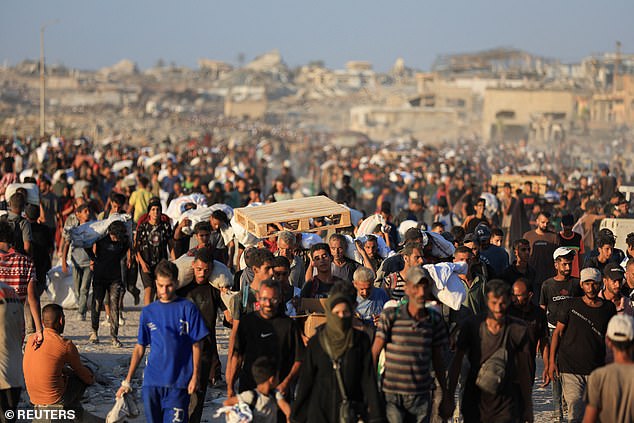 Pictured: Palestinians carry aid supplies that entered Gaza through Israel on Wednesday