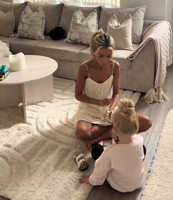 Woman helping young girl put on sandals.