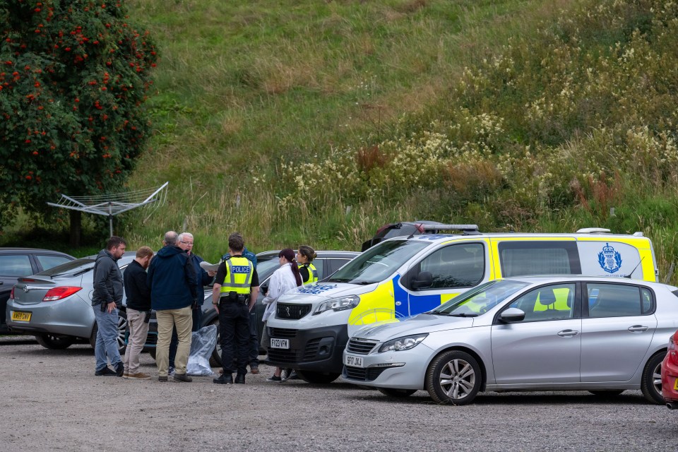 Police officers briefing at a campsite.