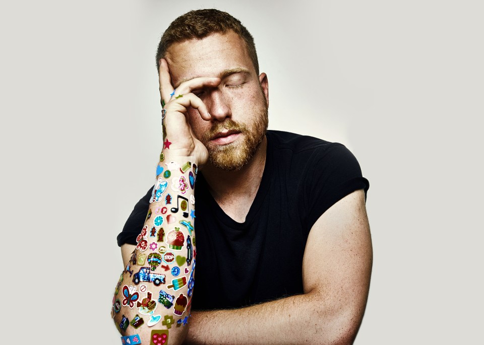 Man with stickers on his arm, eyes closed, hand on his forehead.