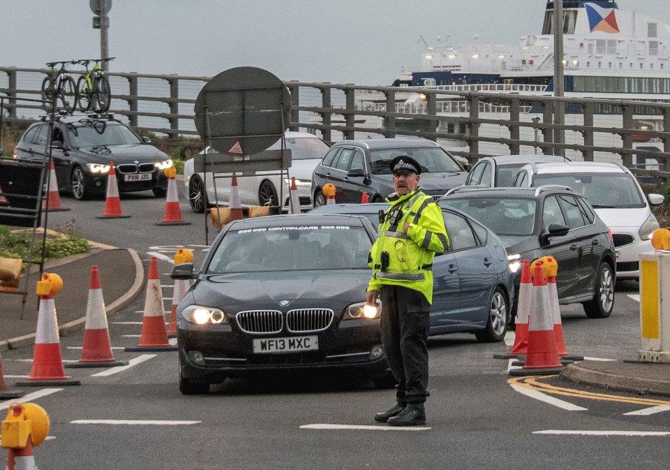 A police officer directs traffic at a busy port.