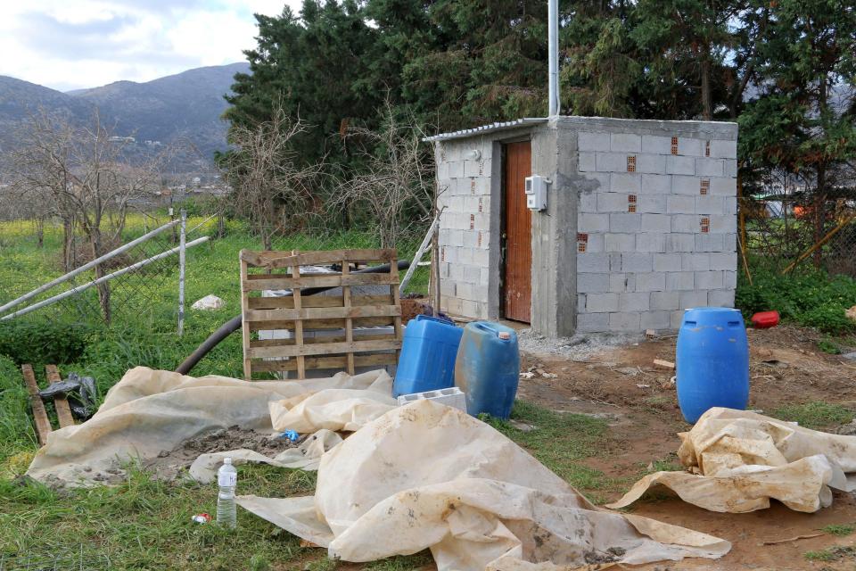 Construction site with a small cinder block building and construction materials.