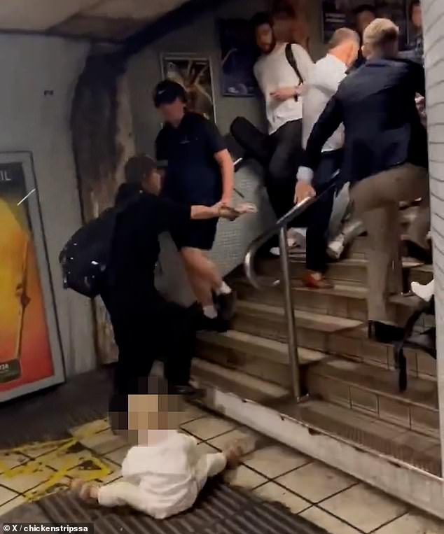A toddler was seen sitting on the floor on their own while the men threw punches just feet away