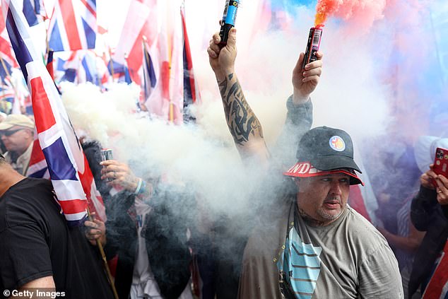 MANCHESTER: Men hold up smoke flares at the protest this Saturday
