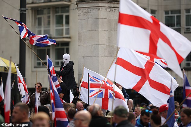 MANCHESTER: A person in a white balaclava waves a Union Jack flag