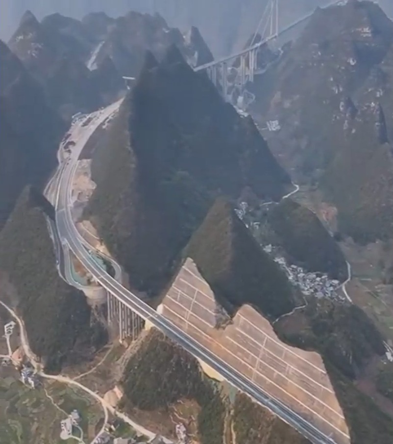 Aerial view of a highway and bridge built through a mountain in China.