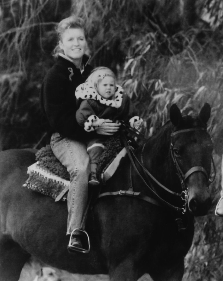 Black and white photo of Sarah Ferguson, Duchess of York, horseback riding with Princess Beatrice.