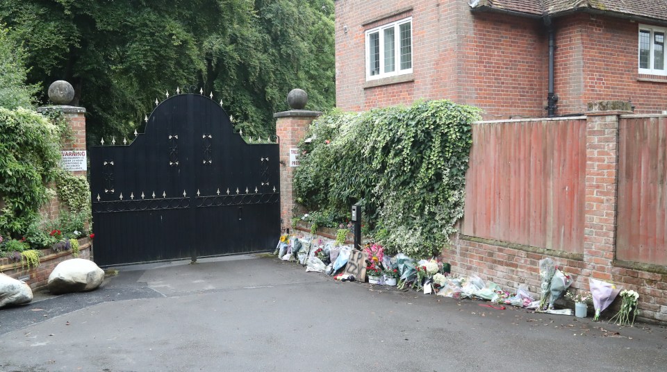 Floral tributes outside a gate.